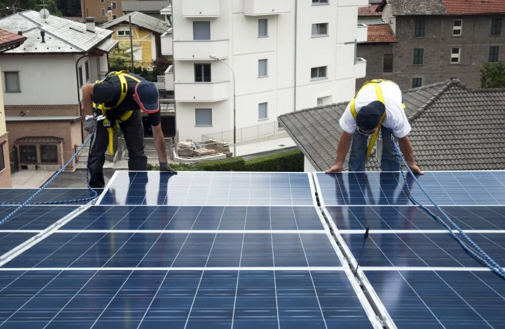 Two engineers installing solar cells on the roof in the city
