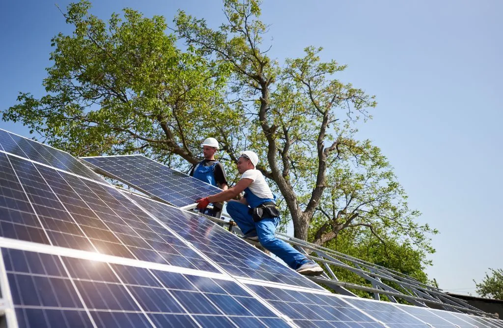 Two solar engineers installing solar cells on a residential building