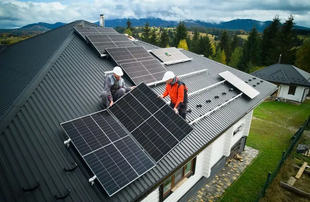 Engineers building photovoltaic solar module station on the house roof.
