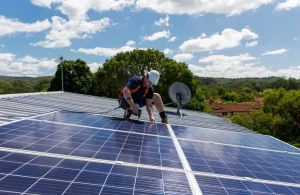 A worker installing photovoltaic solar panels on the house.