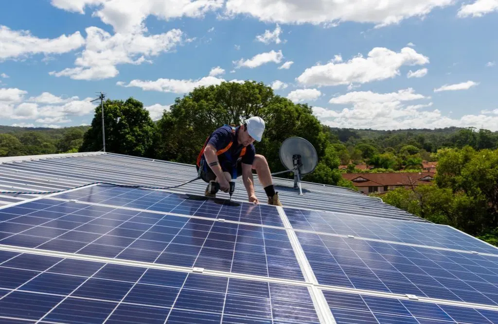 A worker installing photovoltaic solar panels on the house.
