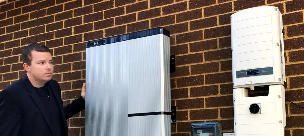 Man standing near LG Chem RESU Solar Battery mounted on the wall.