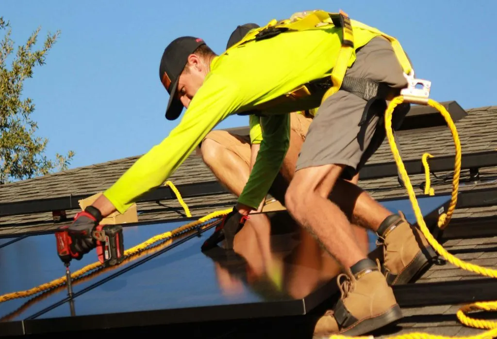  A couple of installers mounting solar panels on the house roof.