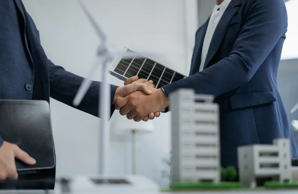 Close-up view of two businessmen shaking hands after signing an agreement on renewable energy.