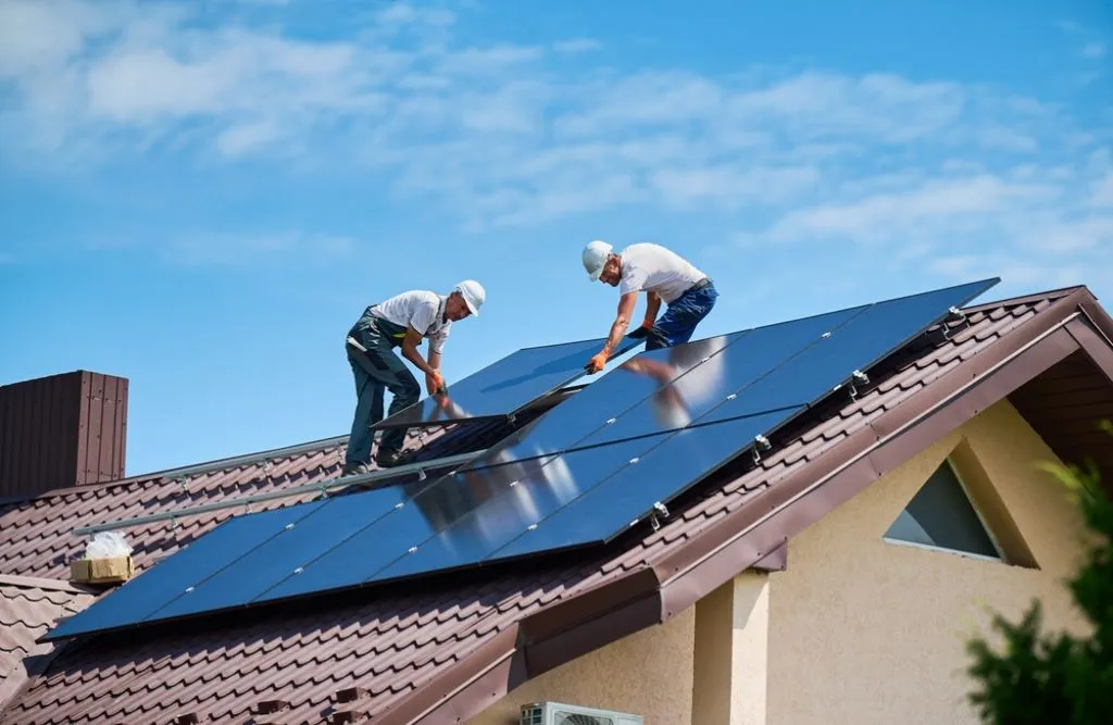 A couple of workers are installing a solar panel system on the house.