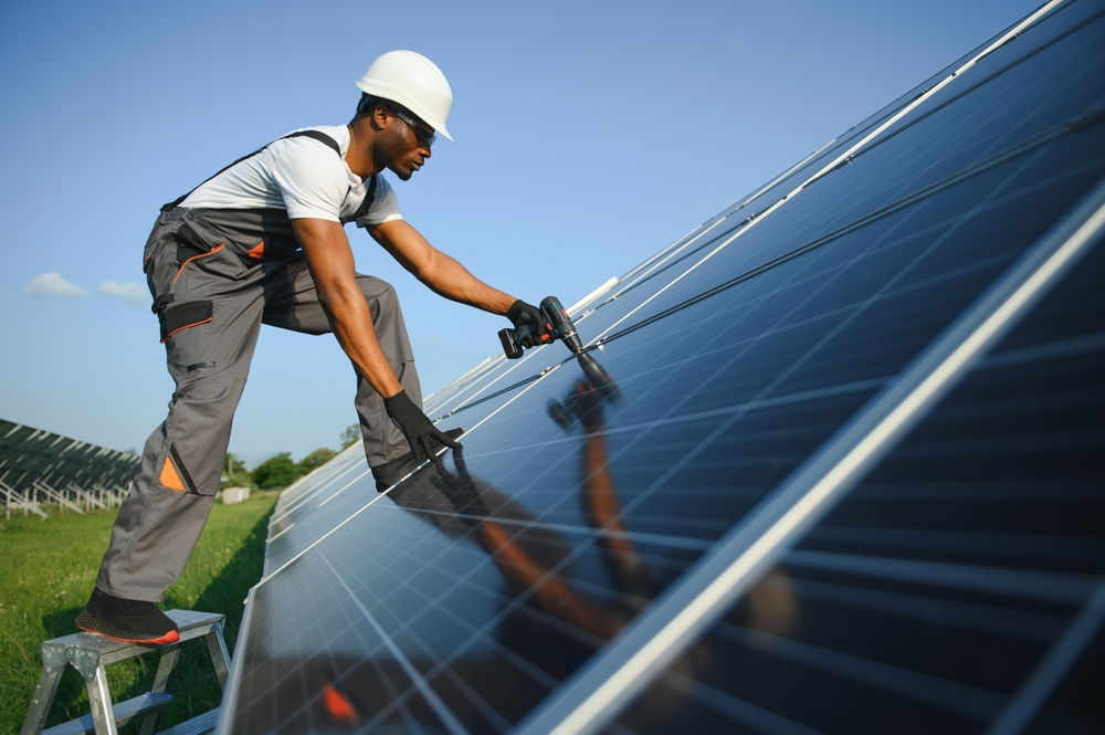 African American engineer repairing solar cells and monitoring solar panel performance.